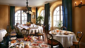 Un espace repas avec plusieurs tables rondes recouvertes de nappes blanches, entourées de chaises.