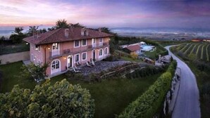 Une grande maison à deux étages, dotée d’un toit en tuiles, d’une piscine et d’un jardin bien entretenu.