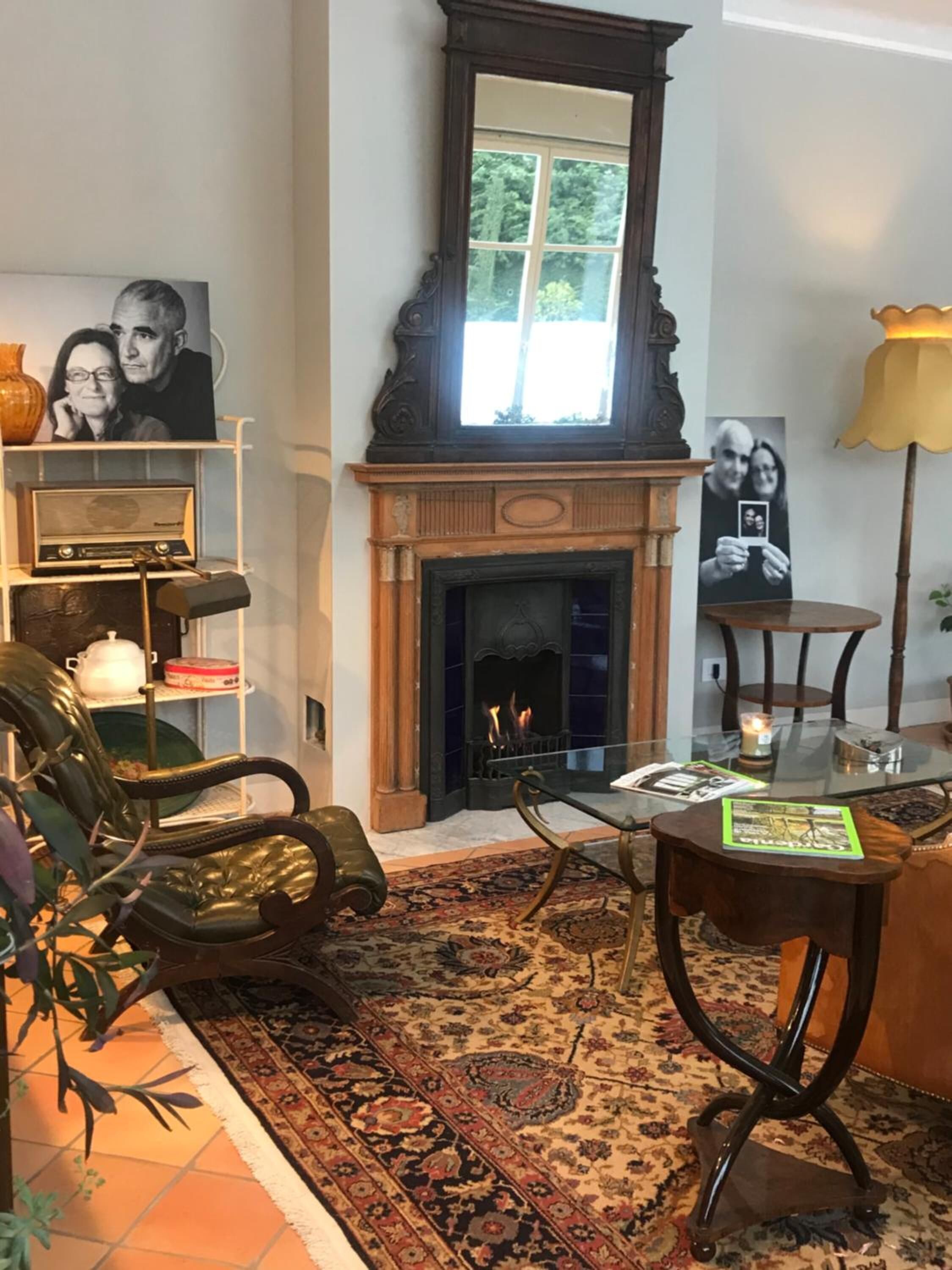 Una sala de estar acogedora con chimenea, una estantería, un sillón de cuero y una mesa redonda con una vela.
