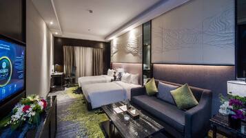 Habitación de hotel con cama, sofá, mesa de centro, televisor y decoración de pared.