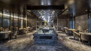 Ein modernes Restaurant mit einer zentralen Bar, Marmorböden und einer Glasdecke.