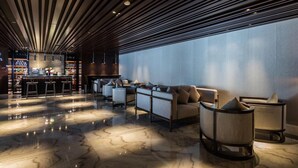 Ein moderner Lounge-Bereich mit Bar, Sitzgelegenheiten und einem großen Fenster.