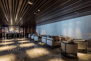 A modern lounge area with a bar, seating, and a large window.