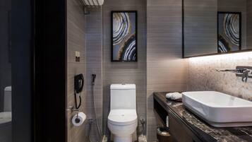 A modern bathroom with a marble floor, a white toilet, a large sink, and a mirror with artwork above it.