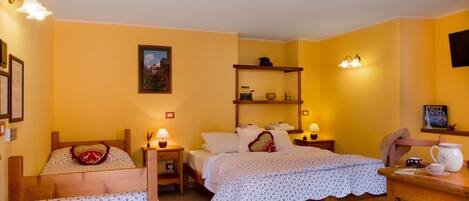Ein gemütliches Schlafzimmer mit zwei Betten, einem Holztisch und einem Regal mit persönlichen Gegenständen.