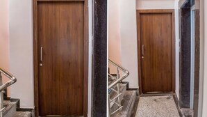 A wooden door with a handle, a metal handrail, and a carpeted staircase. - Treebo Naunidh Suites (Pune)