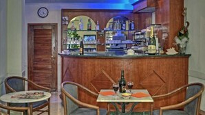 Una zona de bar con muebles de madera, un reloj y una variedad de botellas y vasos.