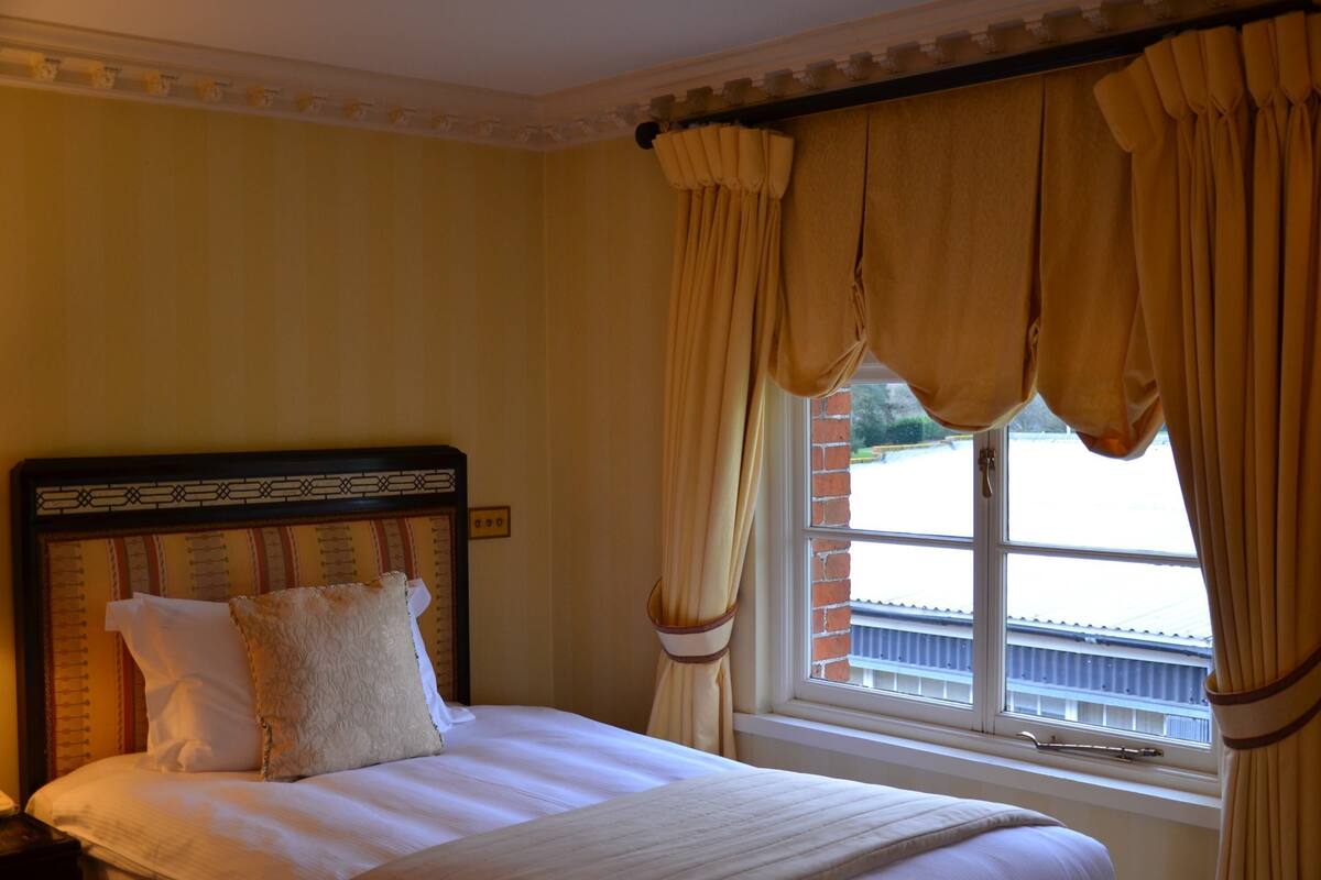 Ein Hotelzimmer mit einem großen Bett, einem hölzernen Kopfteil und einem Fenster mit Vorhängen.
