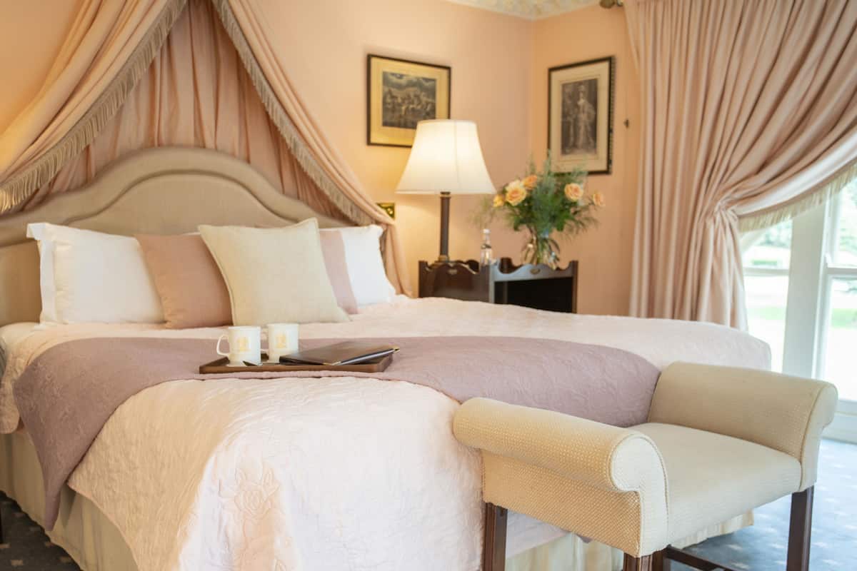 Ein großes Bett mit Baldachin, ein Nachttisch mit Lampe und ein Sessel.