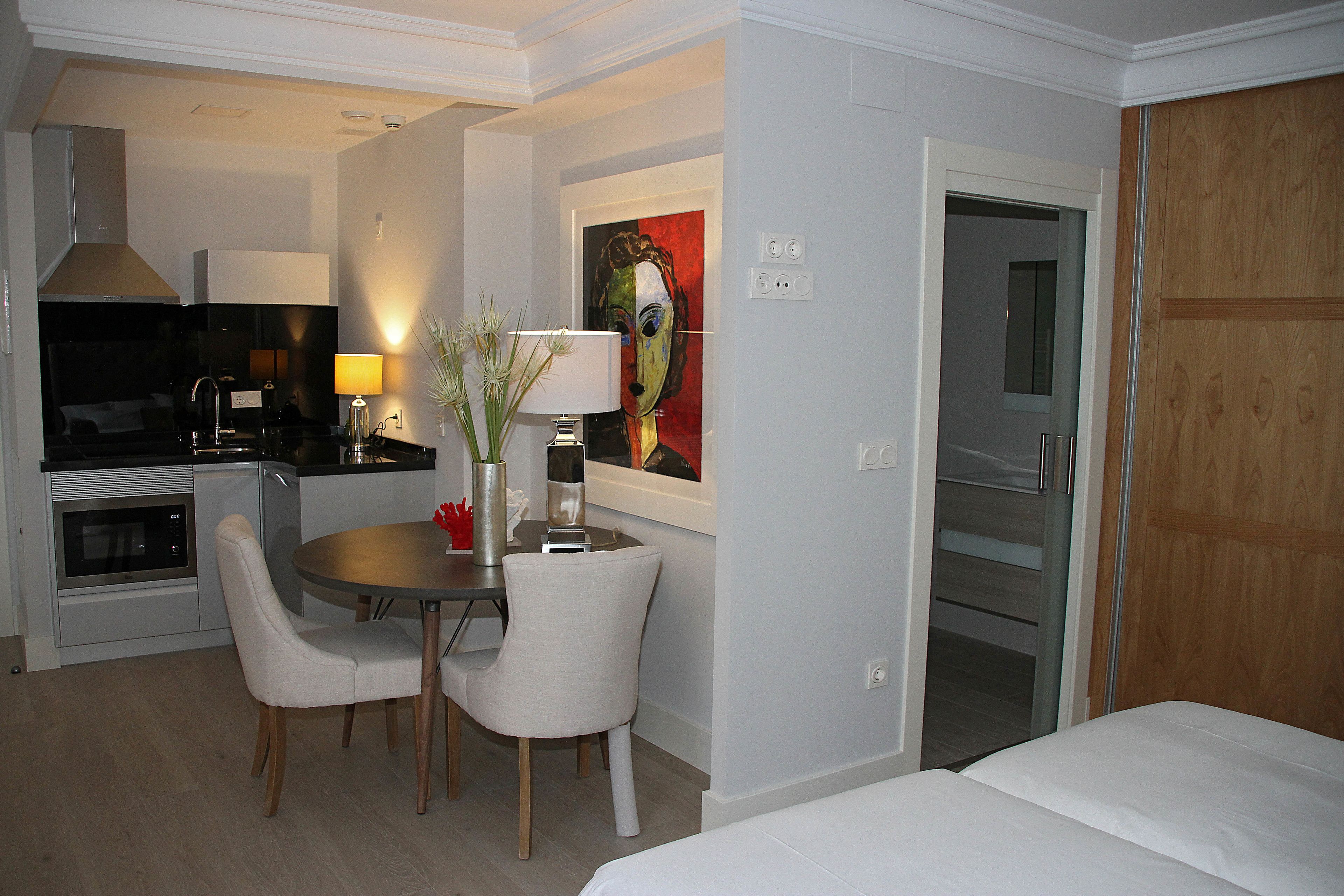 A hotel room with a dining area, a bed, and a wooden wardrobe.