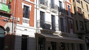 A multi-story building with a cafe on the ground floor. - Principia Suites (León)