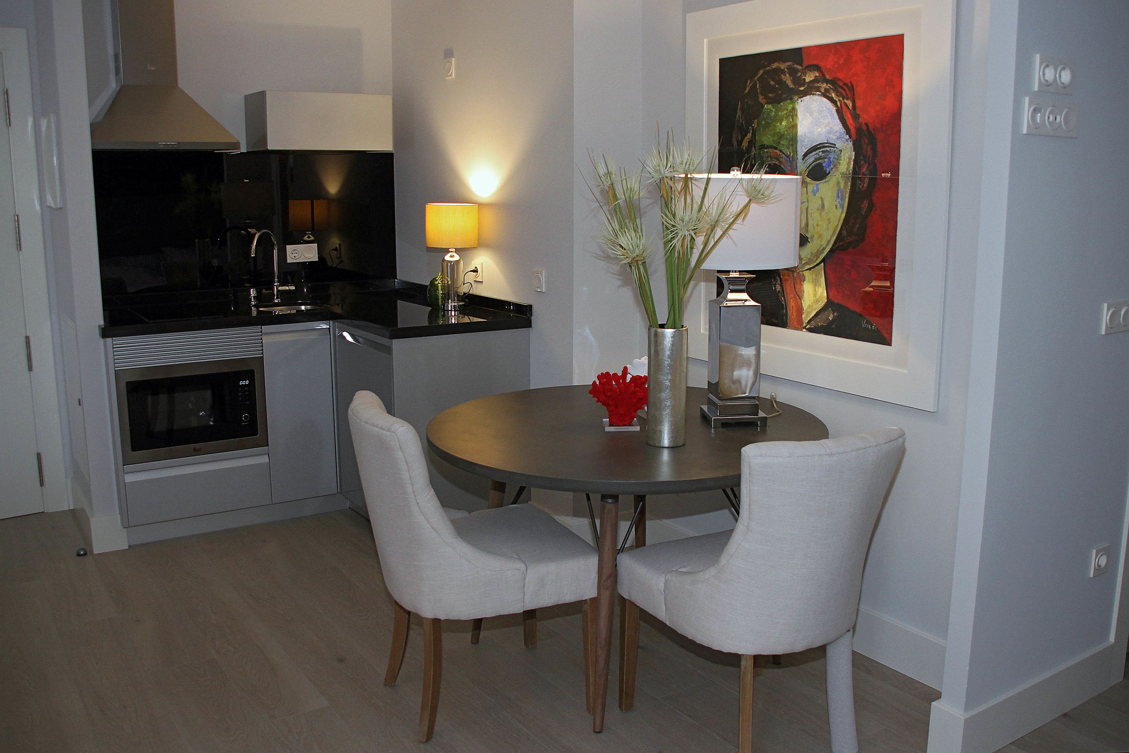 A modern kitchen with a microwave, stove, and dining area with two chairs and a table.
