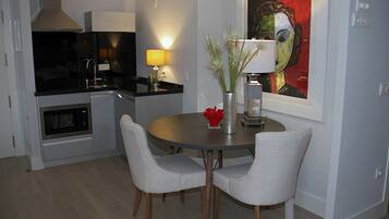 A modern kitchen with a microwave, stove, and dining area with two chairs and a table.
