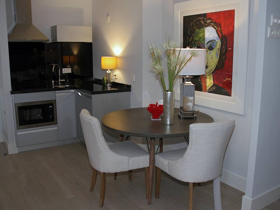A modern kitchen with a microwave, stove, and dining area with two chairs and a table.