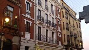 A multi-story building with a cafe on the ground floor. - Principia Suites (León)