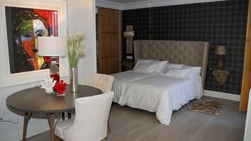 A hotel room with a bed, a desk, a chair, a lamp, a painting, and a rug.