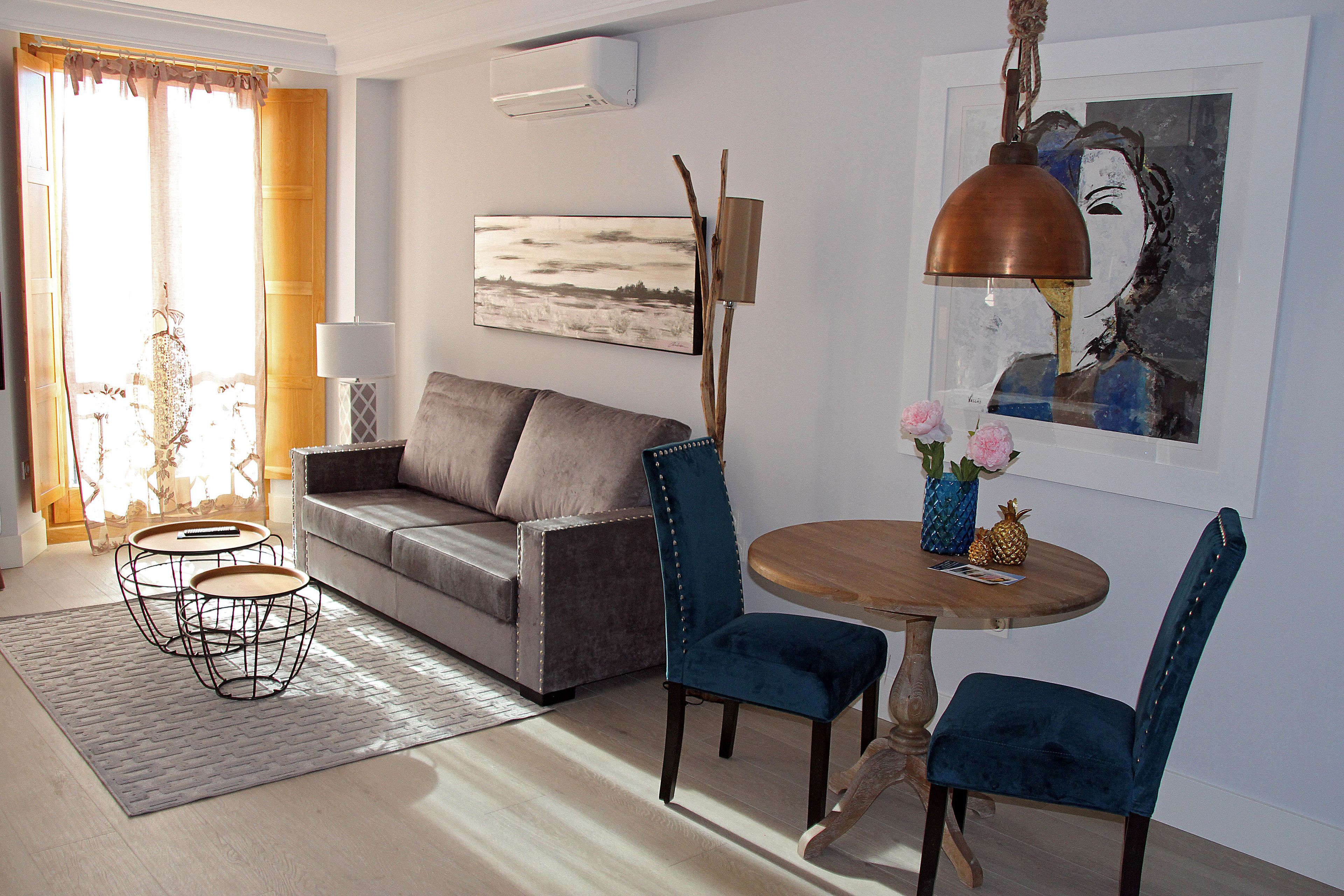Una sala de estar con un sofá, dos sillones, una mesa de centro, una lámpara y un cuadro en la pared.