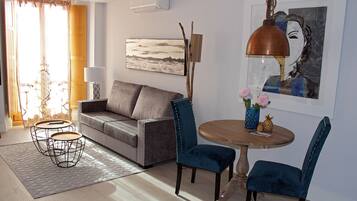 Una sala de estar con un sofá, dos sillones, una mesa de centro, una lámpara y un cuadro en la pared.