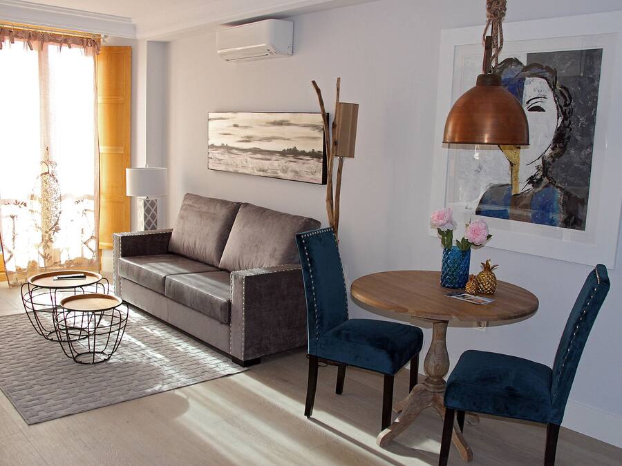Una sala de estar con un sofá, dos sillones, una mesa de centro, una lámpara y un cuadro en la pared.