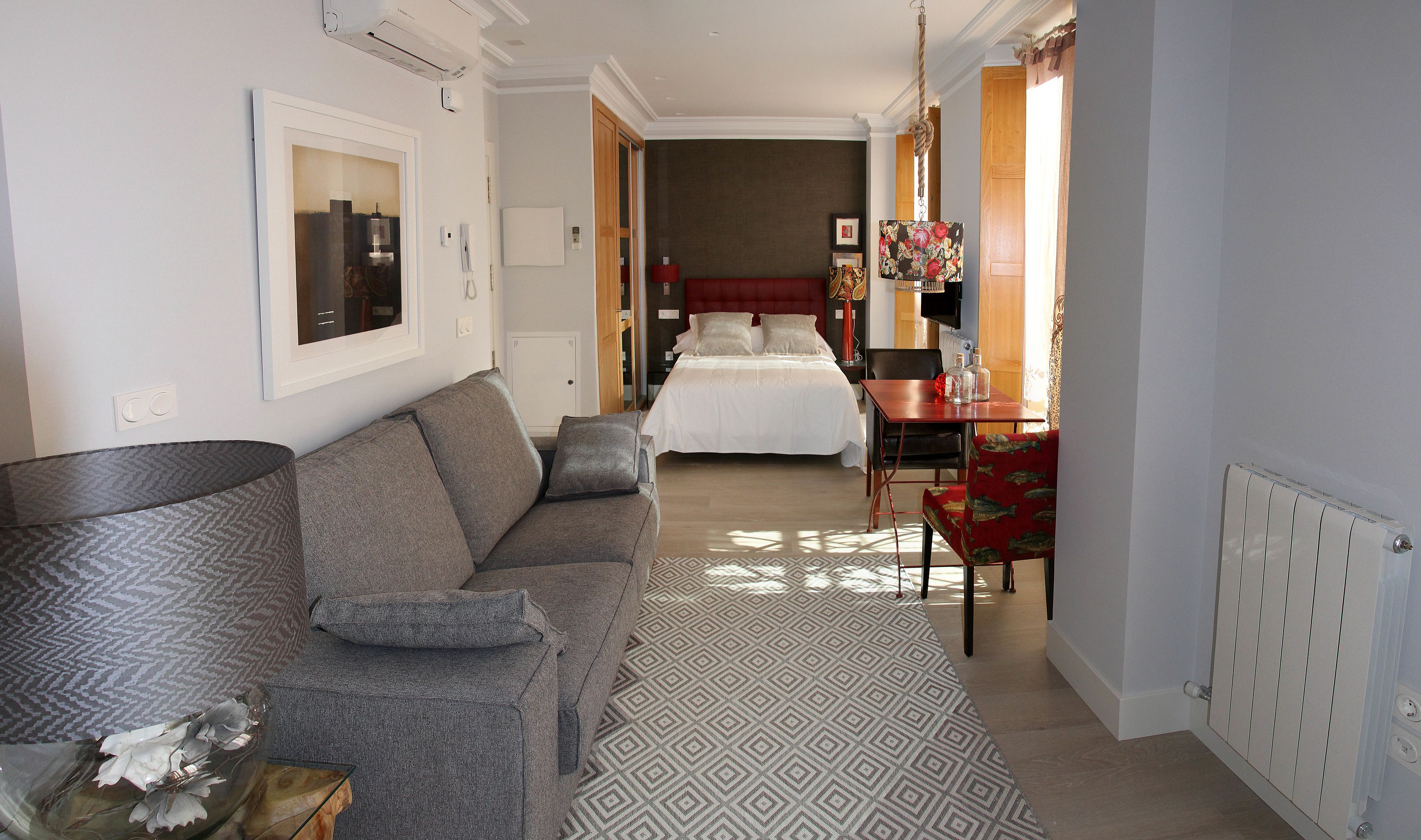 Una habitación de hotel con sofá, cama, mesa de comedor y radiador.