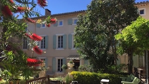 Une cour avec une terrasse en bois, du mobilier d’extérieur et un grand arbre qui offre de l’ombre.