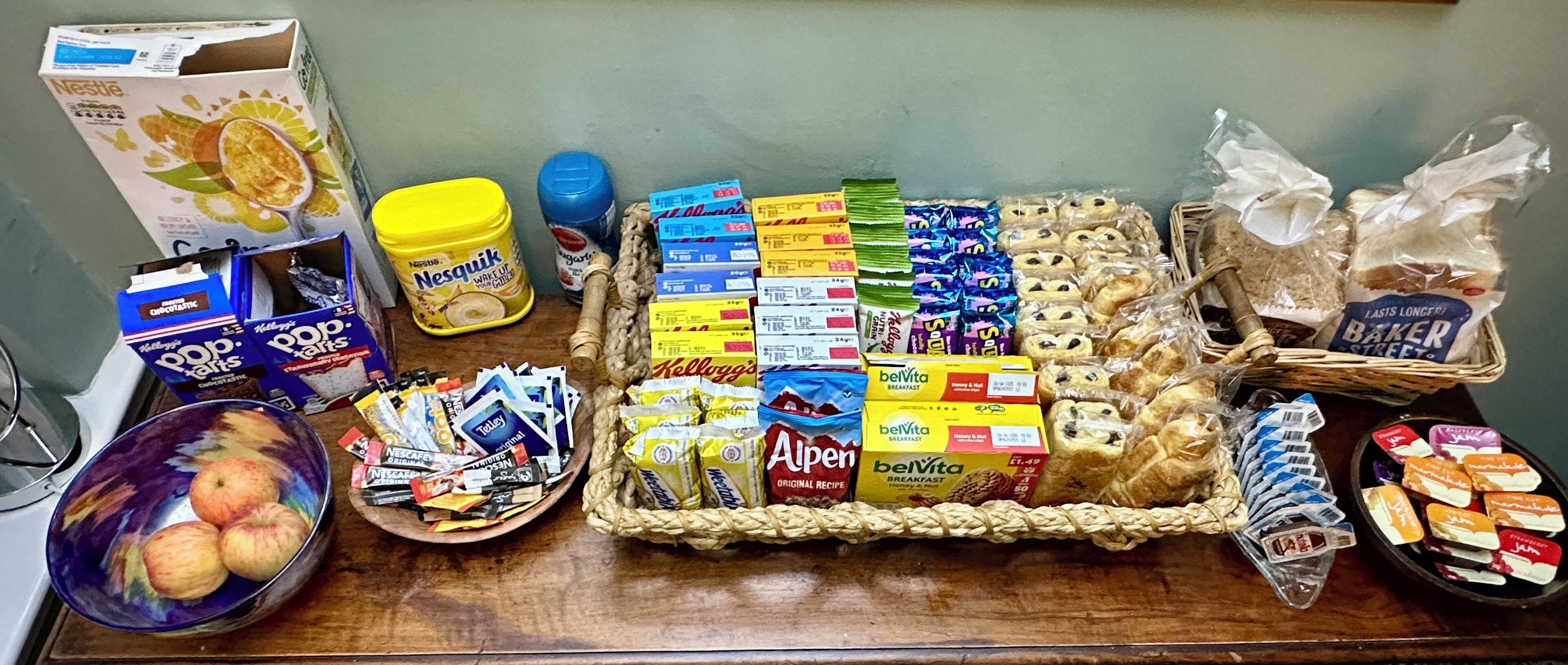 Variedad de alimentos y productos de supermercado sobre una mesa, incluyendo cajas de cereal, aperitivos y alimentos envasados.