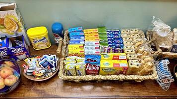 Variedad de alimentos y productos de supermercado sobre una mesa, incluyendo cajas de cereal, aperitivos y alimentos envasados.