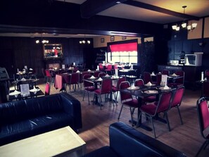 A restaurant with multiple dining tables and chairs, a bar area, and a seating area with couches. - The Elbow Room (Kirkcaldy)
