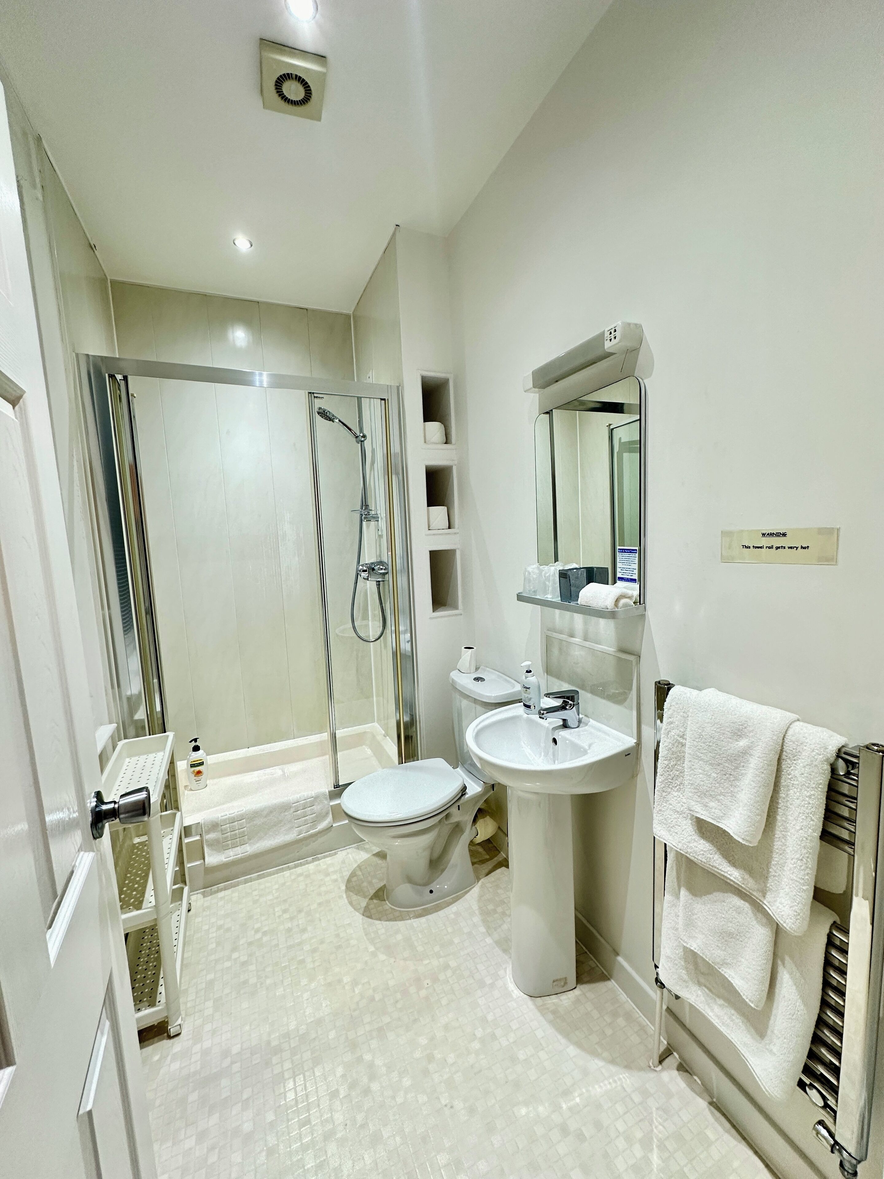 Ein modernes Badezimmer mit Duschkabine, Toilette, Waschbecken und Handtuchhalter.