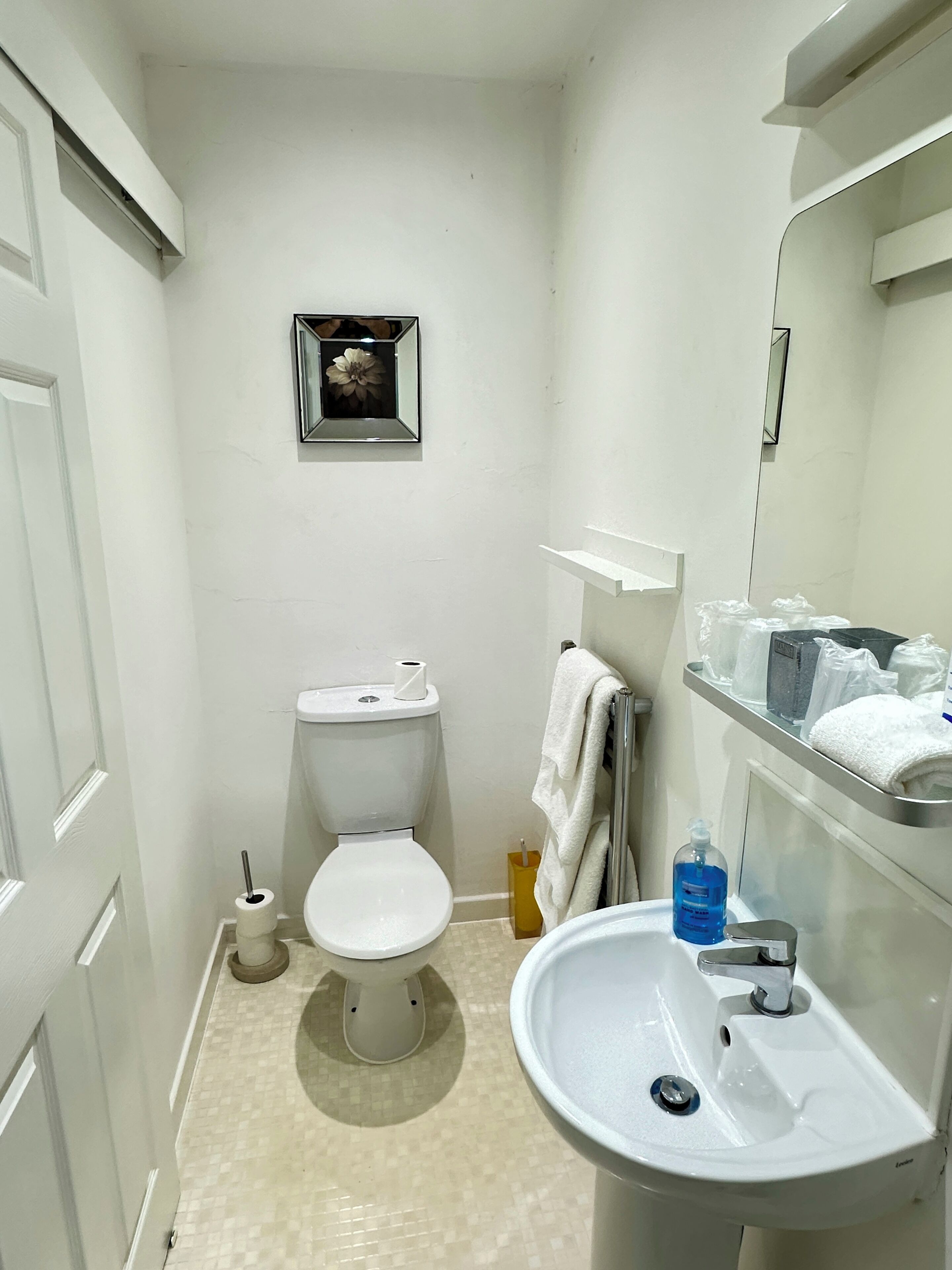 Un baño pequeño con inodoro, lavamanos y espejo.