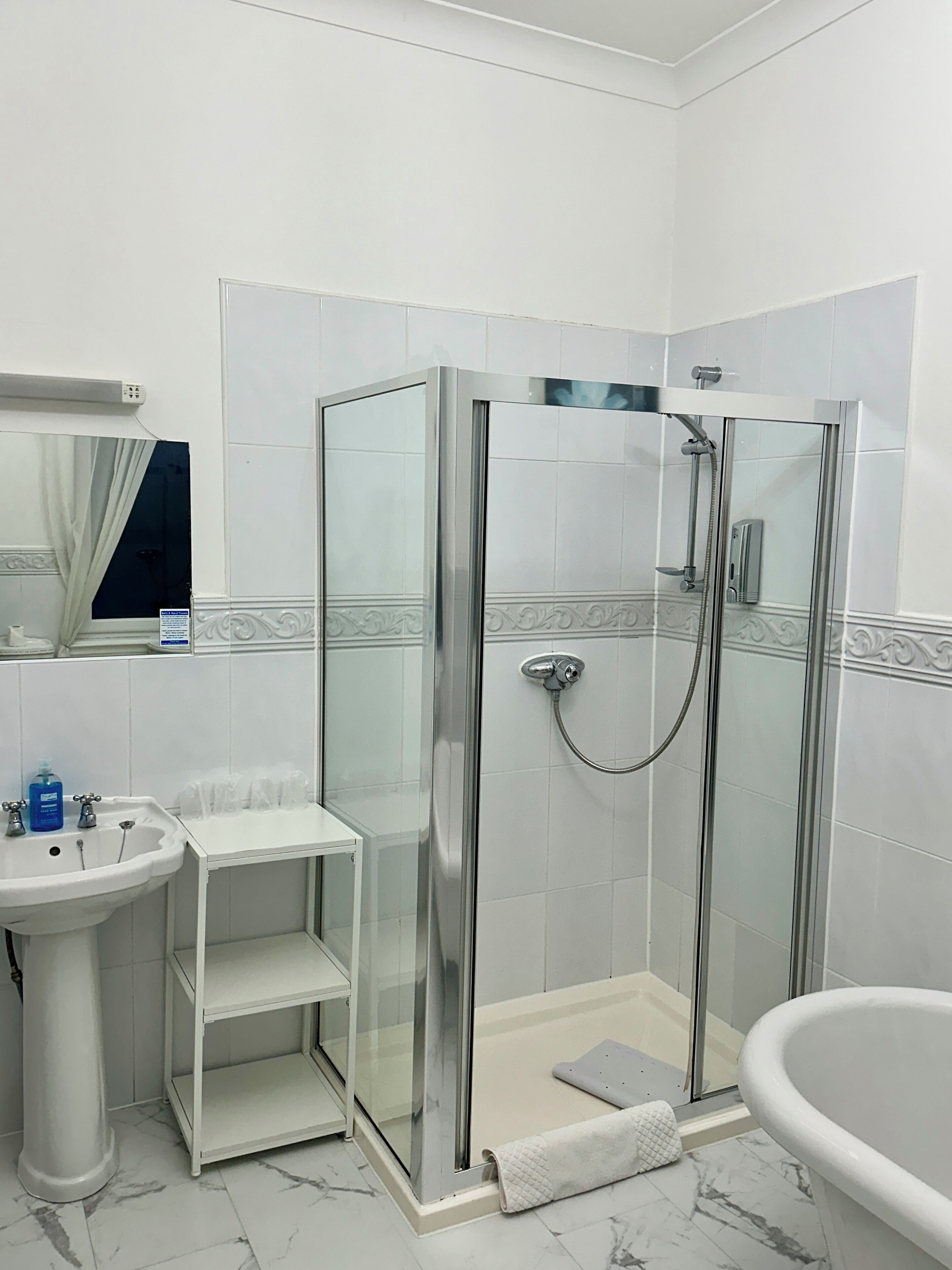 A bathroom with a glass-enclosed shower, a sink, and a bathtub.