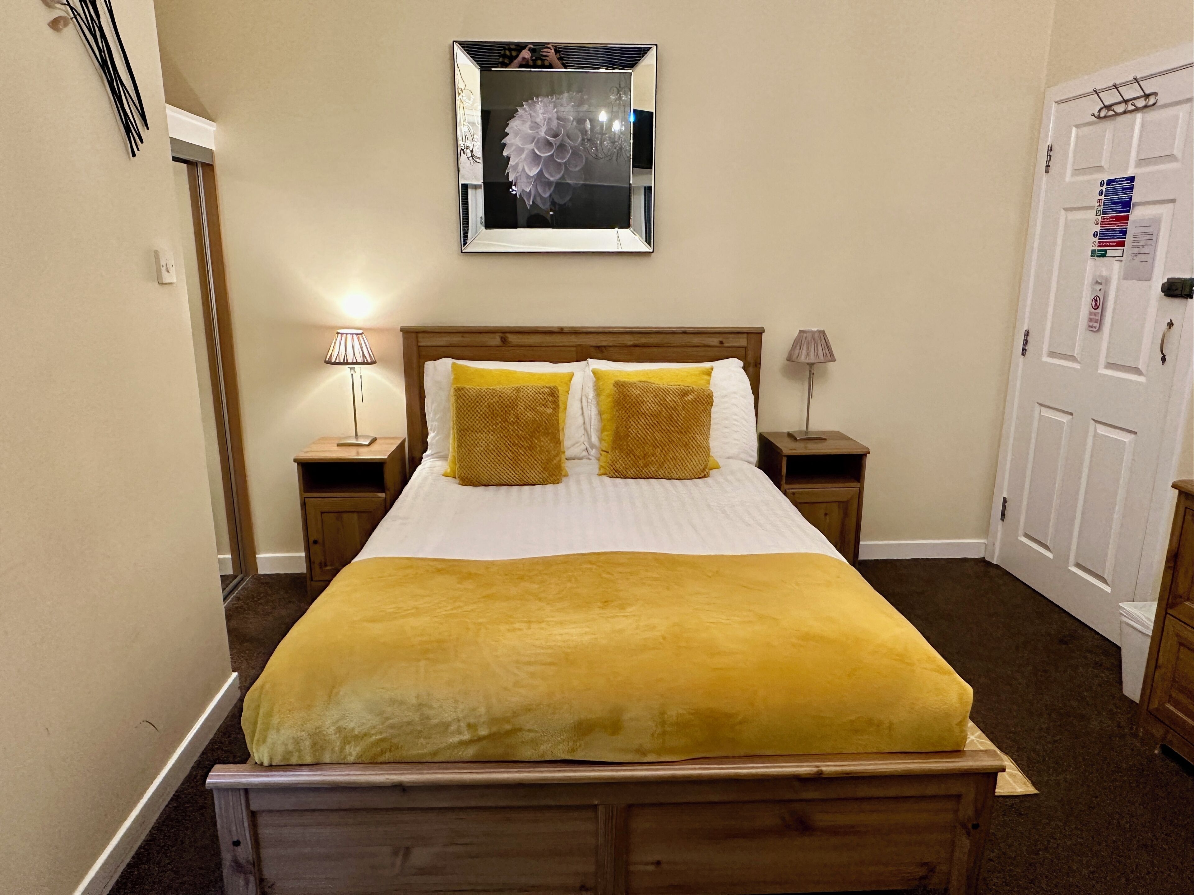 A neatly made bed with a yellow blanket, two matching pillows, and a wooden headboard.