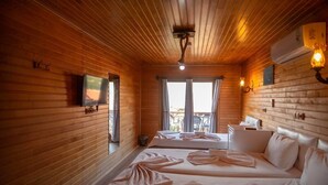 A wooden cabin-style room with two beds, a television, and a balcony with outdoor seating. - 7 Green Adrasan (Kumluca)