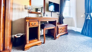 A bedroom with a wooden dresser, a television, a mirror, and a window with curtains. - Invergarry Hotel (Invergarry)