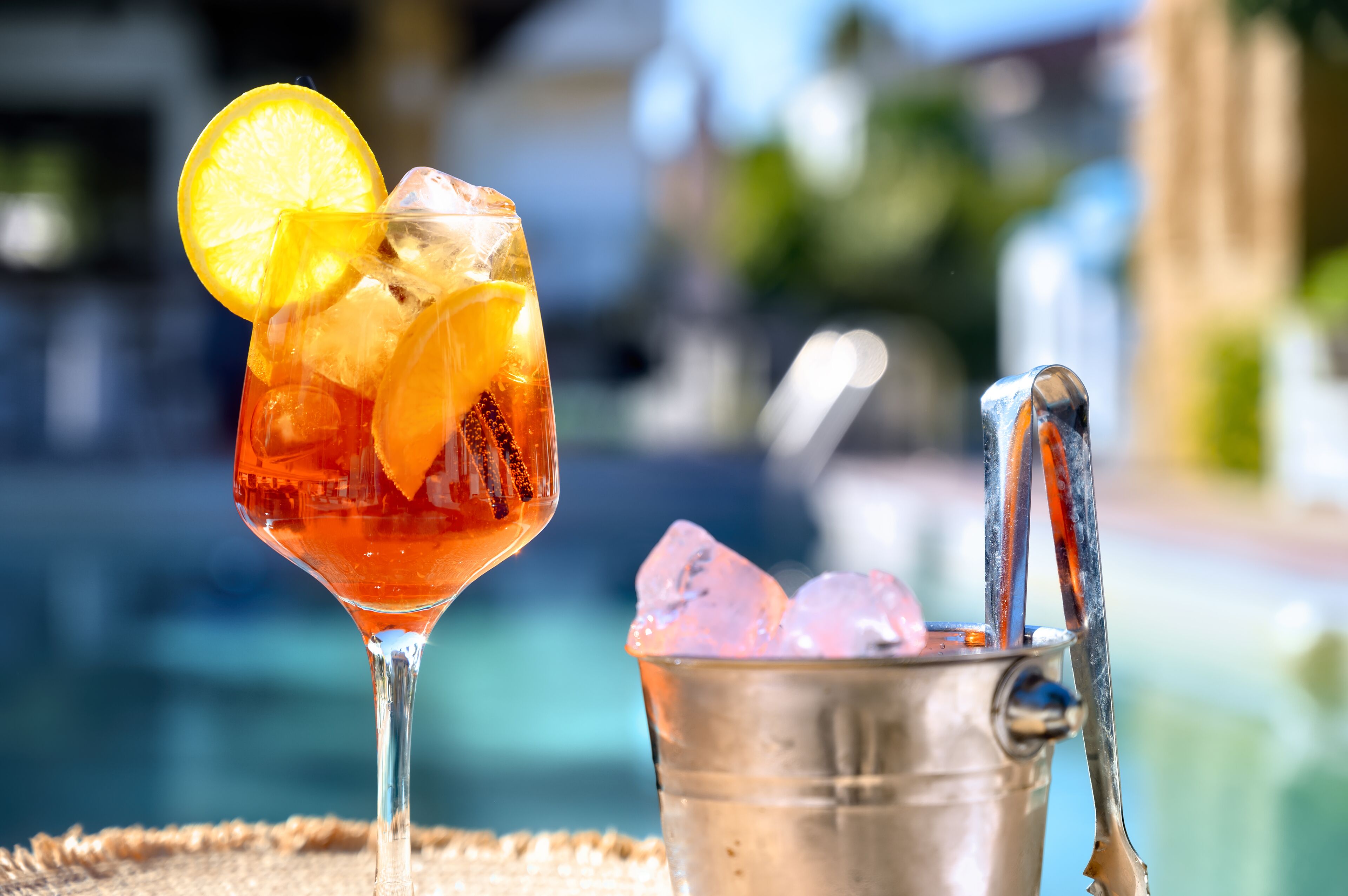 Een cocktailglas met een citroenpartje en ijsblokjes, naast een metalen emmer met een metalen lepel.