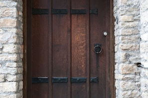 Una puerta de madera con bisagras metálicas y un pomo redondo, incrustada en una pared de piedra.
