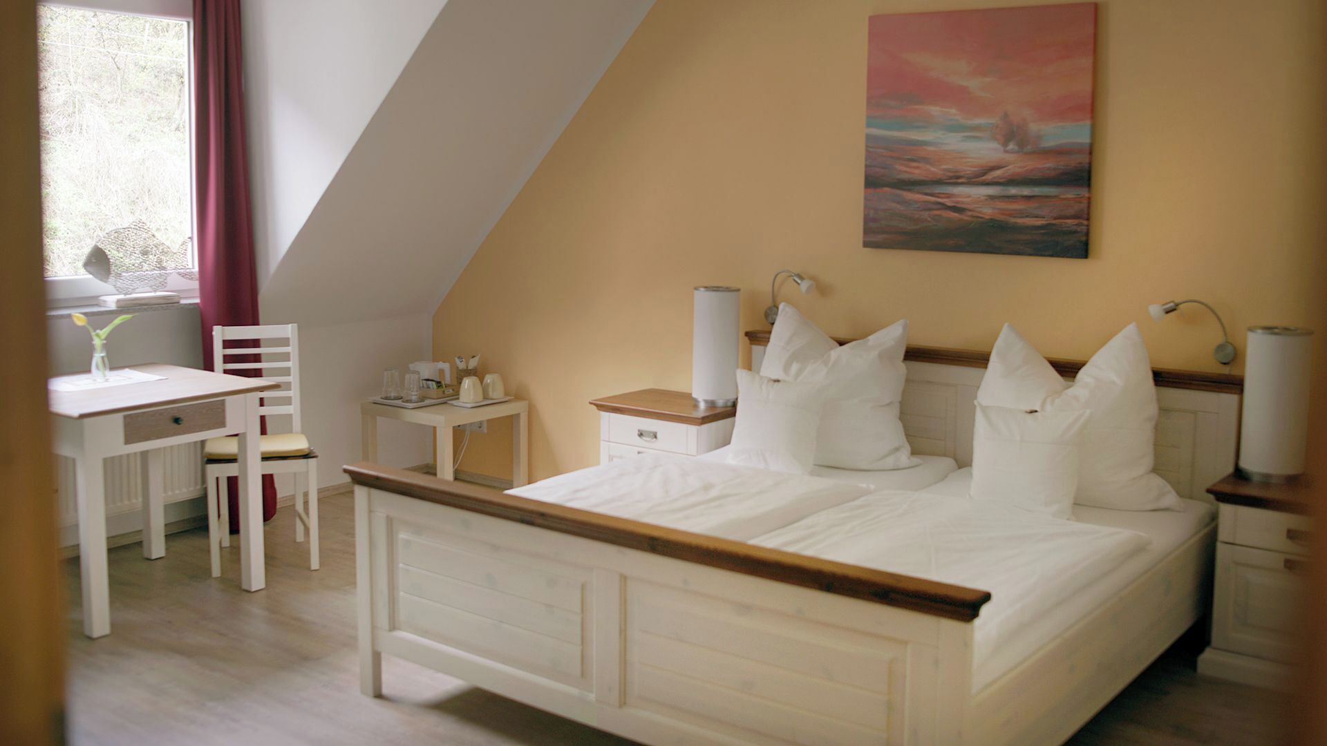 Quarto com uma cama, mesas de cabeceira, escrivaninha e uma cadeira.