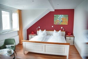 A bedroom with a bed, two bedside tables, a chair, a window, and a colorful painting on the wall. - Haus Am Fluss (Laurenburg)