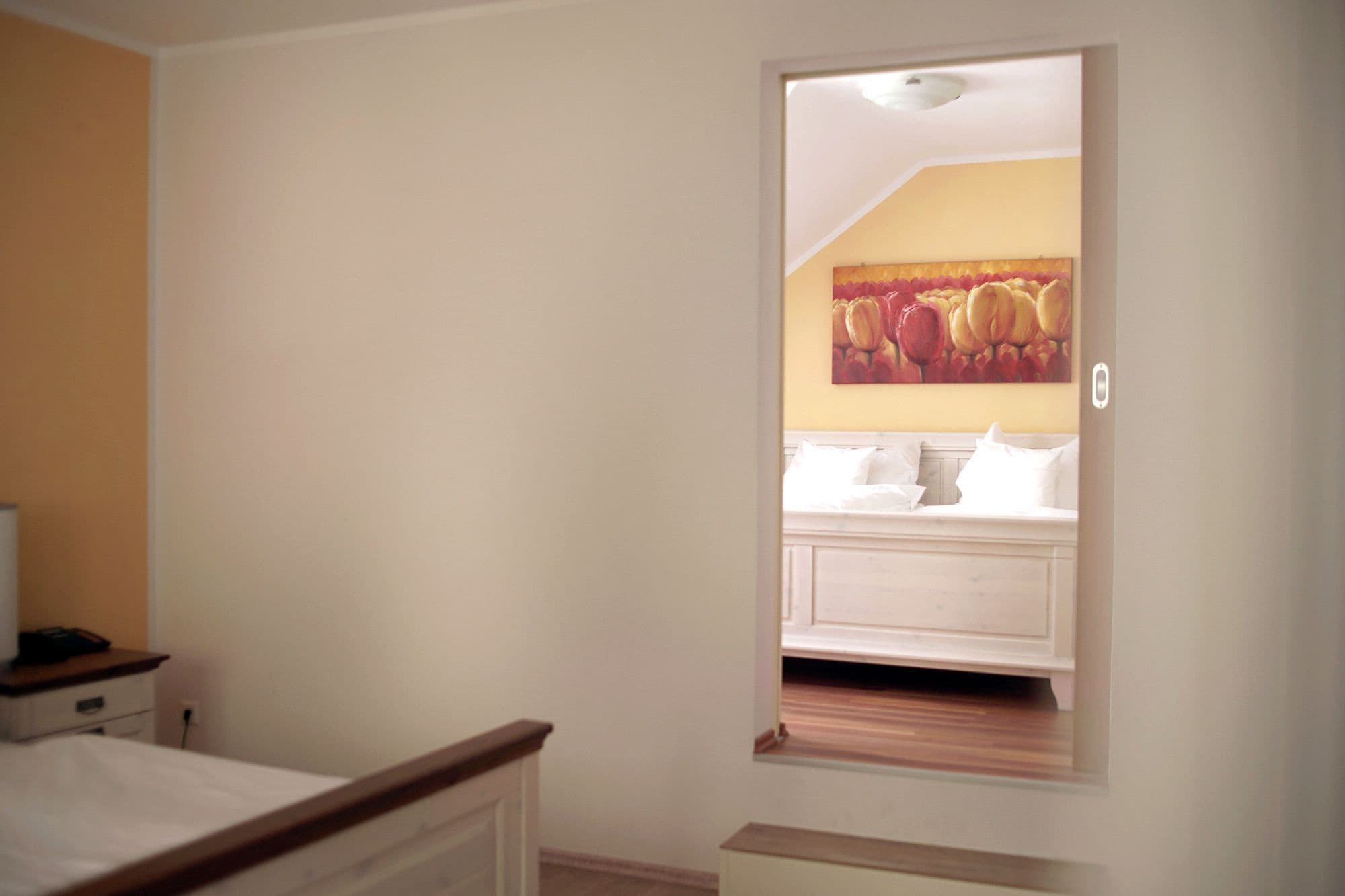 A bedroom with a bed, a nightstand, and a painting of flowers on the wall.
