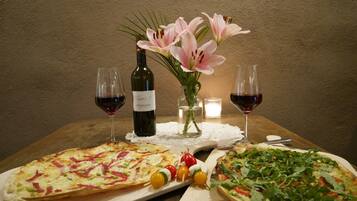 Une table avec deux pizzas, une bouteille de vin et un vase rempli de fleurs.