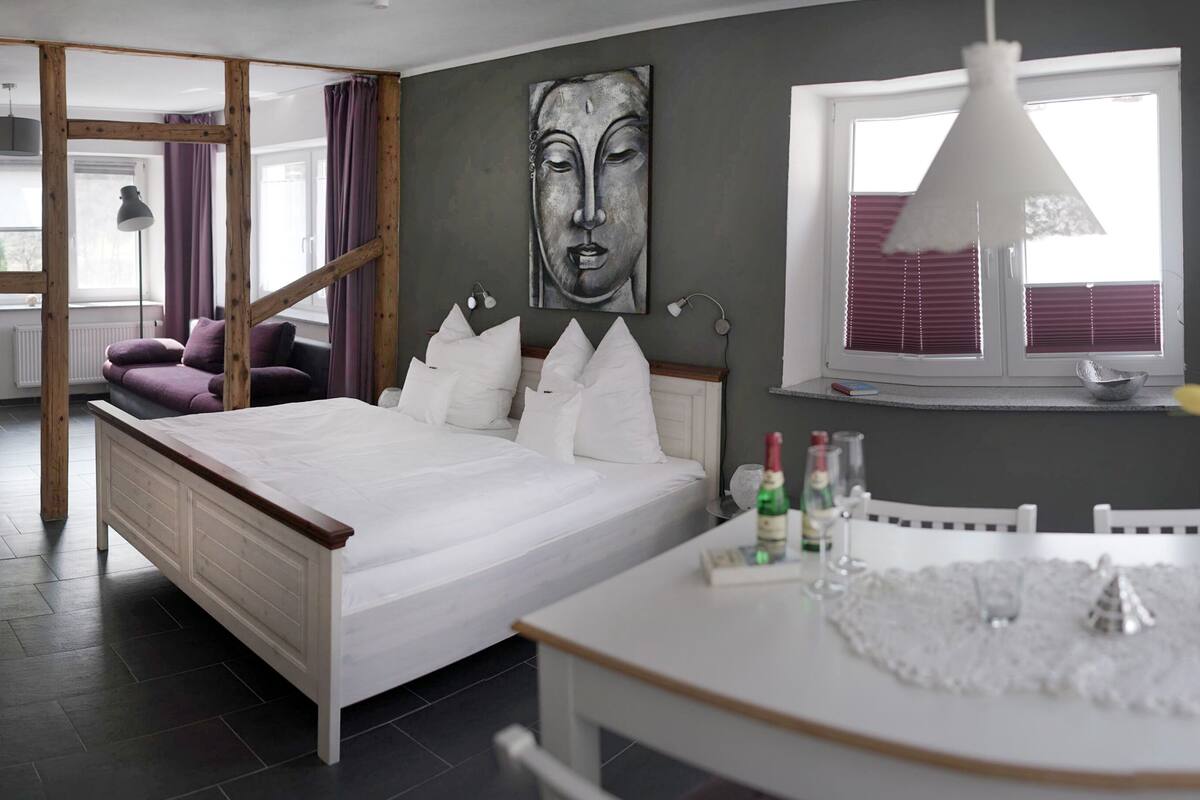 Ein modernes Schlafzimmer mit Bett, Nachttisch und einem Fenster mit Jalousien.