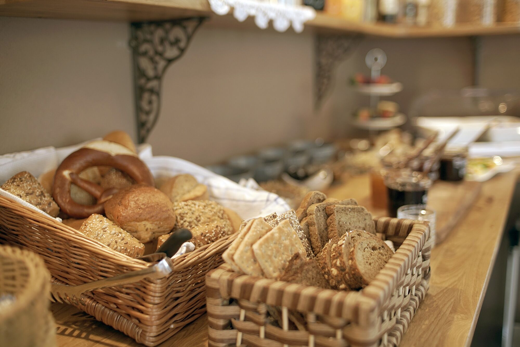 Variedad de panes y pasteles expuestos en cestas de mimbre sobre una mesa de madera.