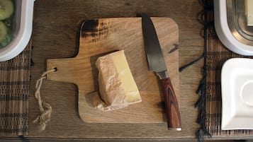 A wooden cutting board with a block of cheese and a knife on a table.