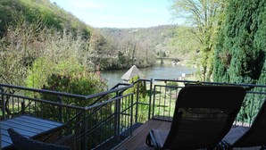 Un balcon donnant sur une rivière, des arbres et un pont.