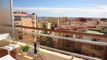 A balcony with a view of a cityscape, including buildings and a body of water.