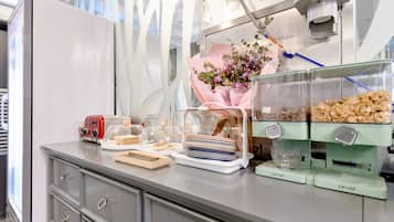 A buffet setup with a toaster, a glass display case with food, and a flower arrangement.