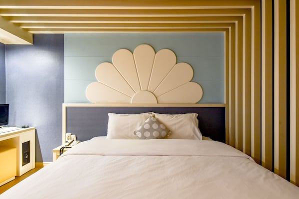 Una habitación de hotel con una cama, un escritorio con ordenador y un cabecero decorativo.