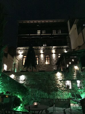 A historic building with multiple illuminated windows and a staircase leading up to the entrance. - Varosi 4 Seasons (Edessa)