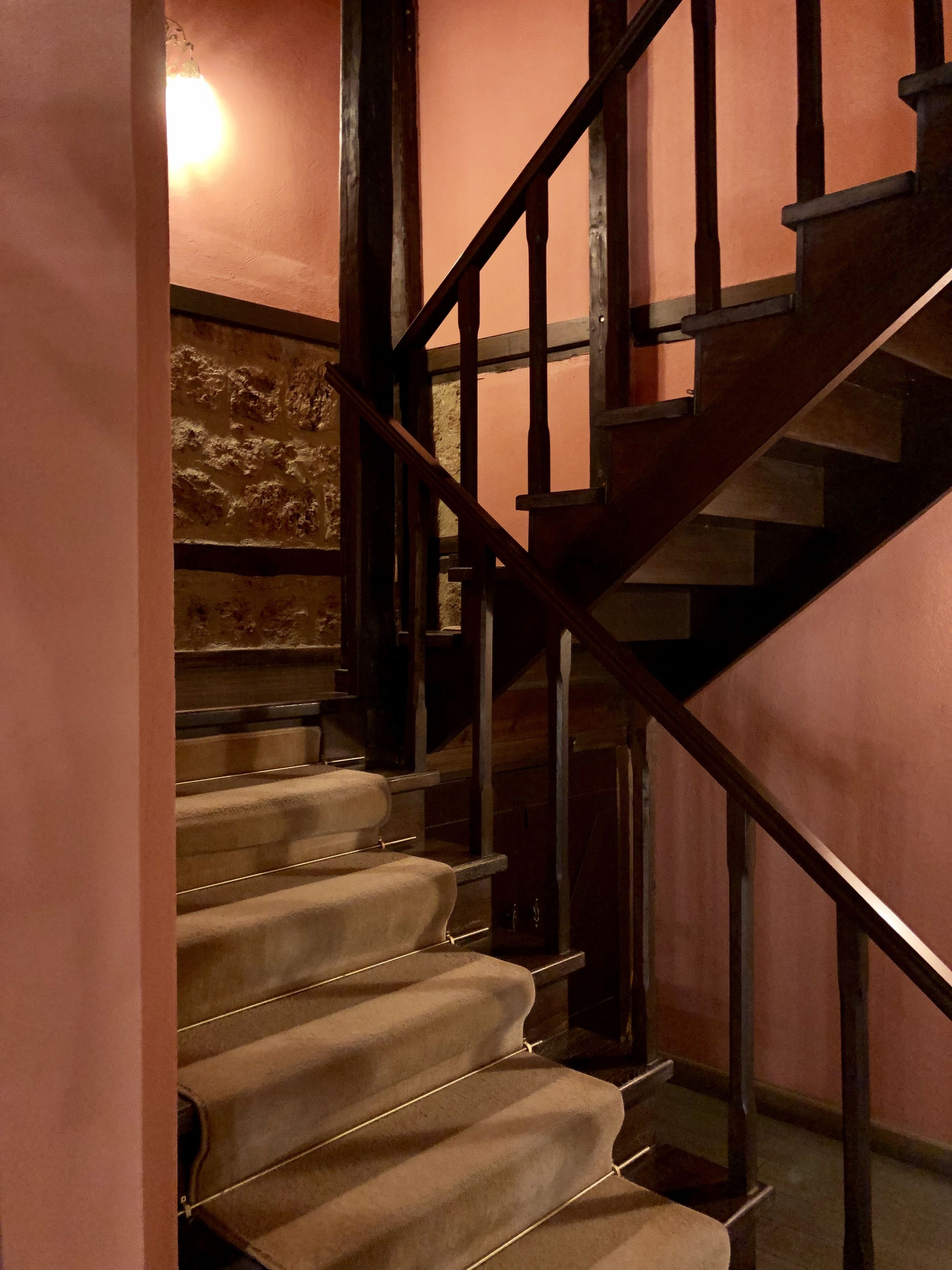 Una escalera con barandillas de madera y peldaños alfombrados.