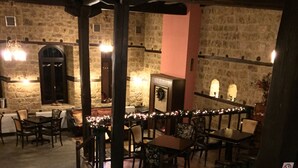 A stone-walled room with a glass floor, wooden furniture, and a fireplace. - Varosi 4 Seasons (Edessa)